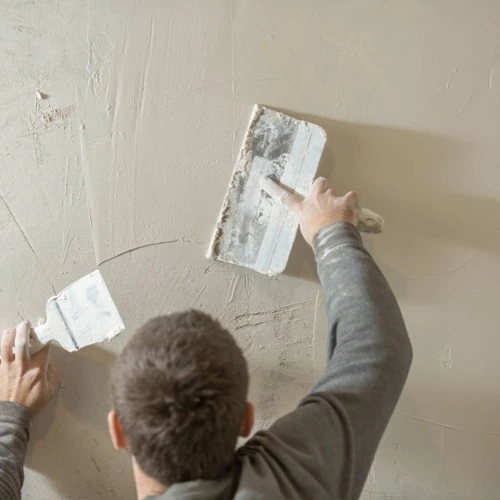 a-man-stands-at-a-rough-plastered-wall
